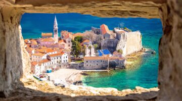 Blick durch ein rustikales Steinmaueröffnung auf die malerische Altstadt von Budva in Montenegro mit