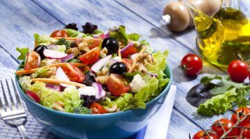 Eine große türkisfarbene Schüssel mit einem bunten gemischten Salat aus Blattsalat, Kirschtomaten, s